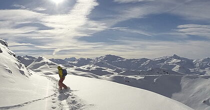Snowboarder in Le Bettaix im Tiefschnee mit Blick über das gesamte Skigebiet.