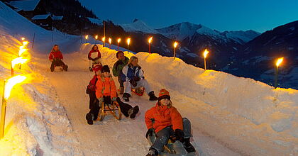 Rodelnde Kinder im Skiurlaub mit hoefer sport und reisen nach bad gastein in Österreich.