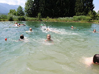 Badesee mit Gästen in der Hausgalerie von der Sommerreise der Ferienanlage Forellenhof in Kärnten in Österreich am Faaker See.
