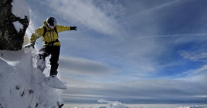 Snowboarder im Sprung im Tiefschnee in Frankreich.