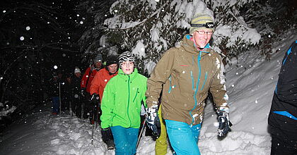 Familien bei einer Fackelwanderung in ihrem Skiurlaub in Werfen in der Sportwelt Ski Amade.